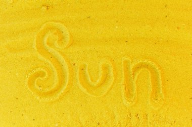 Güneş kelimesi sarı kumsal arka planında yazılıdır. Güneş kavramının işareti ya da sembolü.