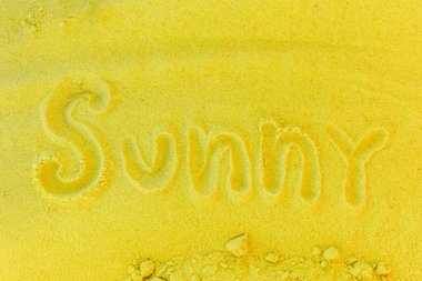 Güneşli kelimesi sarı kumsal arka planında yazılıdır. Güneşli konseptin işareti veya sembolü.