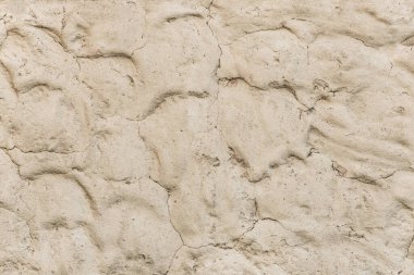 Soyut desenli kum desenli açık bej kil duvar.