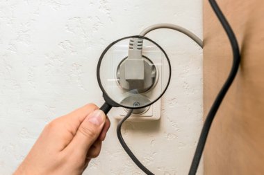 Erkek bir işçi evdeki aletlerin bağlantısını büyüteçle inceliyor..