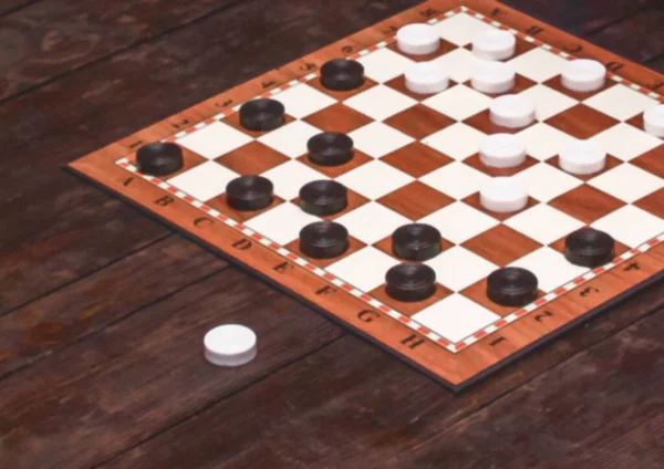 Checkers game. Checkerboard on a wooden table. Board games concept. Blurred background.