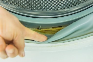 Adamın eli, çamaşır makinesinin eski varil mühründeki kirli suyun kalıntılarını gösteriyor..