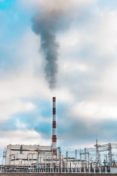 Environmental problem, environmental pollution, smoke from the pipe of an thermal power plant against a blue sky.