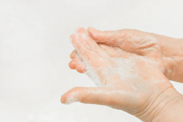 An adult woman\'s hands lathered with soap, close-up. Hand washing and domestic hygiene concept.