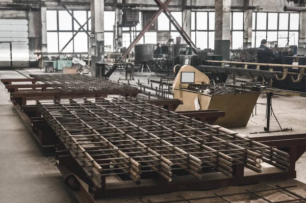 Reinforcement mesh against the background of the production of concrete structures in a workshop at an industrial enterprise.