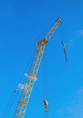 İnşaat alanında mavi gökyüzüne karşı makine endüstriyel vinç ekipmanları.
