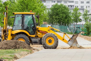 Buldozer veya kazıcı endüstriyel makine inşaat alanındaki binaların arka planındaki kumu temizler.
