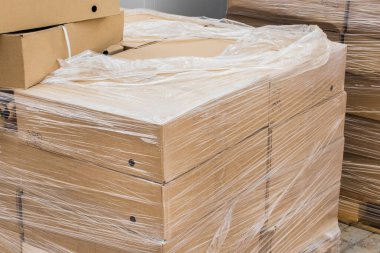 İnşaat alanında naylon ambalaja doldurulmuş inşaat malzemeleriyle dolu karton kutular..