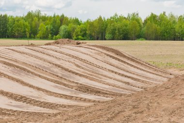 Toprak ve inşaat sahasının düzleştirilmesi, inşaata hazırlık, buldozer veya kazıcı izleri kum arka planında.