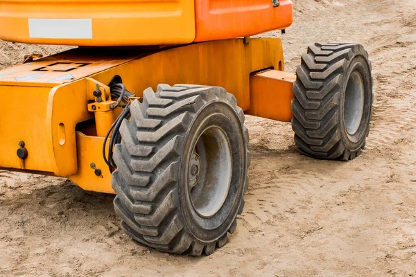 Wheels of industrial lifting transport tire truck against the background of sand at a construction site.