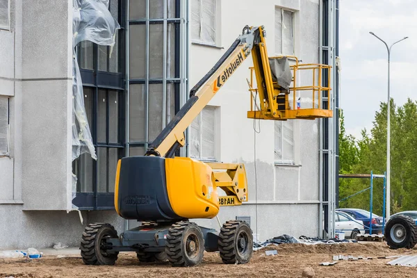 Belarus, Minsk - 28 Mayıs 2020: İnşaat alanındaki yeni modern bir binanın arka planına karşı platformu kaldıran endüstriyel araç.