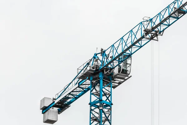 Tower construction building blue crane against the grey sky.