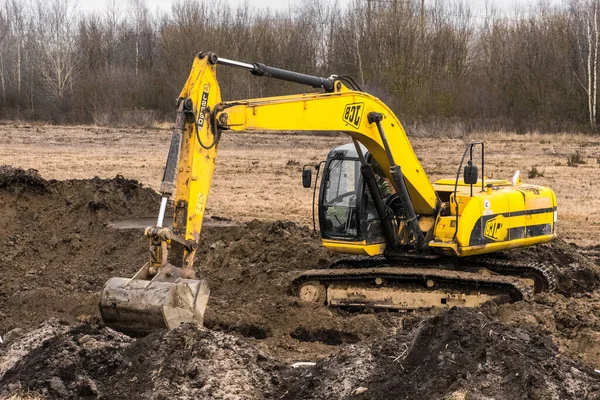 Belarus, Minsk bölgesi - 11 Aralık 2019: Sürüngen kazıcı teçhizatındaki inşaat işçisi sanayi bölgesinde hendek kazıyor. Toprak ve toprakla kazı çalışmaları.