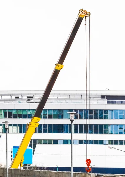 Maskinlyft kran industriell utrustning på en byggarbetsplats i bakgrunden av en ny, modern fasad av en urban byggnad — Stockfoto