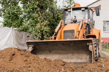 Kazı makinesi veya buldozer kovası sanayi bölgesinde veya şantiyede zemini veya yolu dümdüz ediyor.
