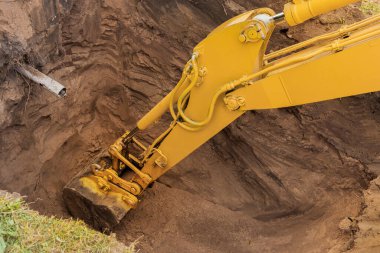 Kazı kovasının hidrolik pistonu inşaat alanında yakın plan bir çukur kazıyor..