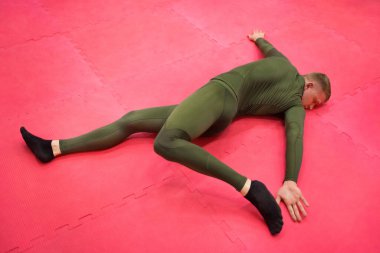 Yeşil termal takım elbiseli genç sporcu spor salonunda egzersiz yapıyor..