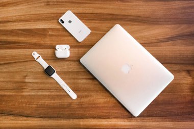 Belarus, Minsk bölgesi - 17 Mart 2020: Dizüstü bilgisayar, iphone, elma saati ve ahşap masa arkasındaki uçak podları.
