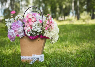 Bir demet çiçek demet desenli karton kutunun içinde park çimenlerinin üzerinde.