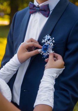 Düğün için. Gelinin elleri düğün eldivenleriyle süslemeyi damadın mavi takım elbisesinde beyaz gömlek ve papyonlu gül şeklinde ayarlar..
