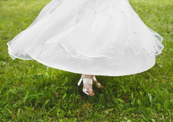 新娘的白色婚纱在公园的绿草上飘扬 — 图库照片