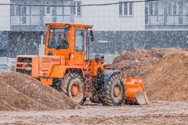 Belarus, Minsk - 14 Mart 2020: Kış mevsiminde bir inşaat alanında endüstriyel makine traktörü kumu düzleştirir.