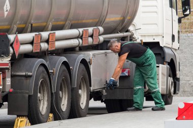 Belarus, Gomel bölgesi - 21 Ağustos 2020: Yeşil tulumlu bir kamyon şoförü, arabanın sağlığını kontrol etmek için bir alet çantası açar. Yakıt ve benzin taşıma ve teslimatı. Petrol ve doğalgaz.