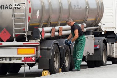 Belarus, Gomel bölgesi - 21 Ağustos 2020: Tulumlu bir kamyon şoförü makineyi topraklama kablosunu ya da kabloyu kavrıyor. Yakıt ve benzin taşıma ve teslimatı. Petrol ve doğalgaz.
