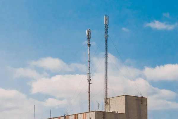 青い空に対するレンガ造りの建物の屋根の上に2つの携帯電話の通信アンテナ — ストック写真