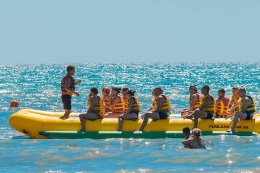 Ukrayna, Demir Liman - 24 Ağustos 2020: Bir adam şişme muz sürerken güvenlik brifingi veriyor. Eğlence, aşırı dinlenme ve deniz arka planında eğlence.