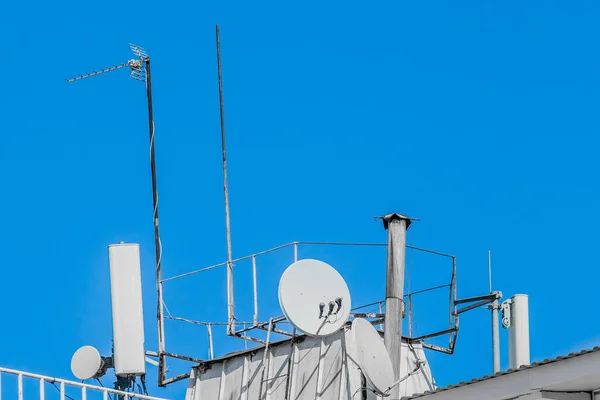 青い空に対する建物の屋根の上の技術のテレビやモバイル信号古いシステム — ストック写真