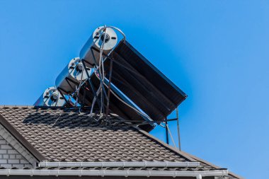 Termal güneş panelleri ve su ısıtıcısı alternatif su ısıtma teknolojileri evin çatısında mavi gökyüzüne karşı..