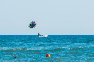 Ukrayna, Demir Liman - 25 Ağustos 2020: Ekstrem sporlar ve heyecan verici dinlenme. Ufuk çizgisinin arka planında mavi denizde bir paraşut taşıyan motorlu teknede turist taşıyan bir grup insan..