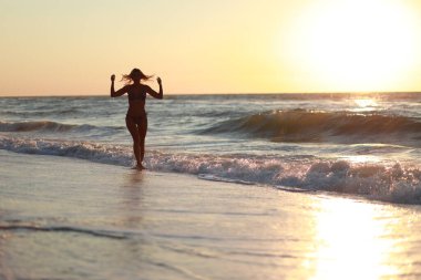 Güzel duygusal model kız denize su sıçratıyor ve gülüyor.