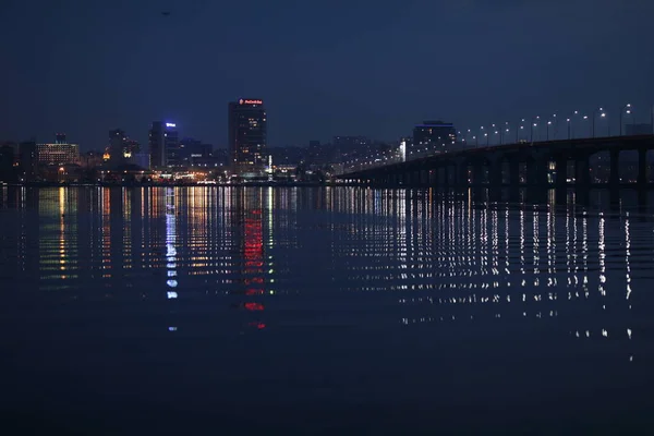 Nacht stad als het is mooie lichten op de achtergrond van de rivier — Stockfoto