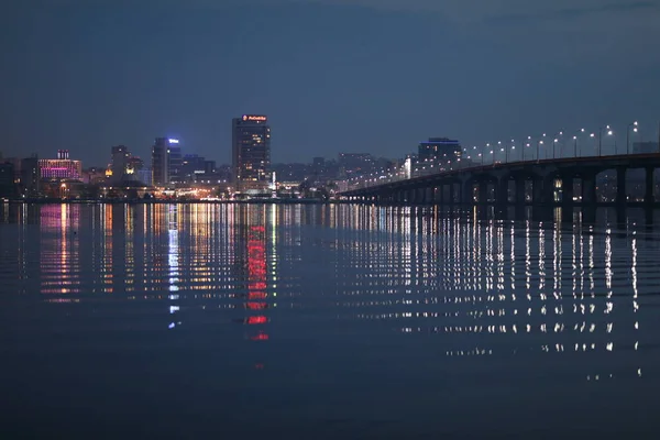 Nacht stad als het is mooie lichten op de achtergrond van de rivier — Stockfoto