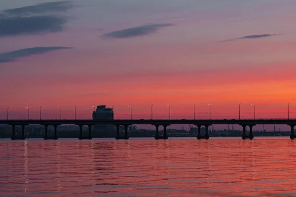 Pôr do sol colorido tarde da noite pela água na estrada — Fotografia de Stock