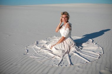 Gelinlik giymiş güzel gelin kumların üzerinde.