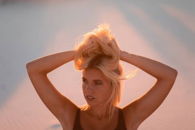 Güzel sarışın okyanusun yakınındaki kumlu sahilde dinleniyor.