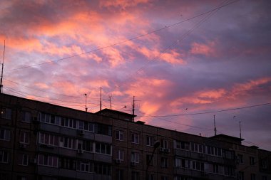 Güzel yüzen bulutlar şehrin üzerinde parlak kırmızı yüzüyor.