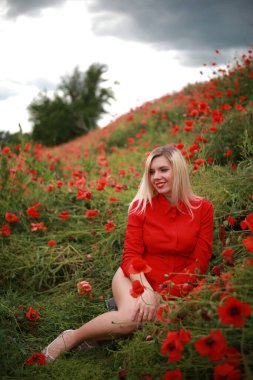 Kırmızılı gelinciklerle tarlada güzel bir kız.