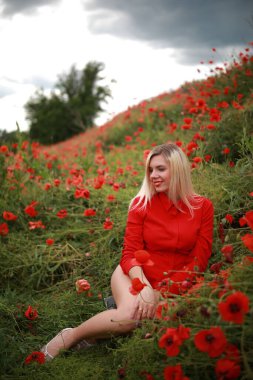Kırmızılı gelinciklerle tarlada güzel bir kız.