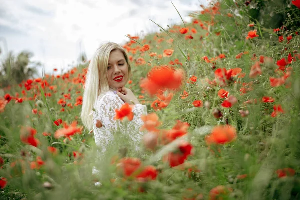 Hermosa chica en un campo con amapolas rojas en un traje de cuerpo transparente —  Fotos de Stock