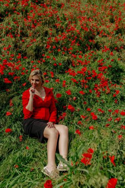 Kırmızılı gelinciklerle tarlada güzel bir kız.