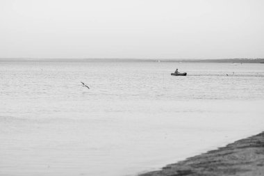 Okyanus kenarında günbatımı güneşi, berrak su ve kumlu gök mavisi plajı.