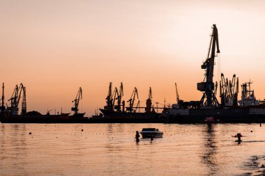 Okyanus kenarında günbatımı güneşi, berrak su ve kumlu gök mavisi plajı.