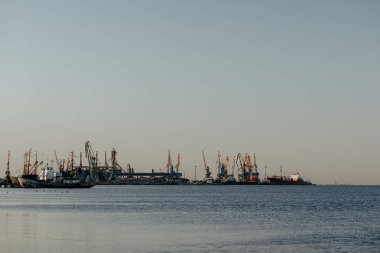 Okyanus kenarında günbatımı güneşi, berrak su ve kumlu gök mavisi plajı.