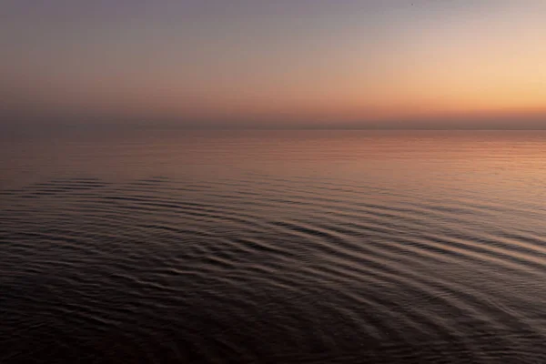 Sol al atardecer junto al océano, agua clara y playa azul arenosa —  Fotos de Stock