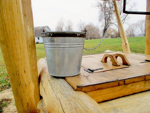 一桶水矗立在一口旧木井上 — 图库照片