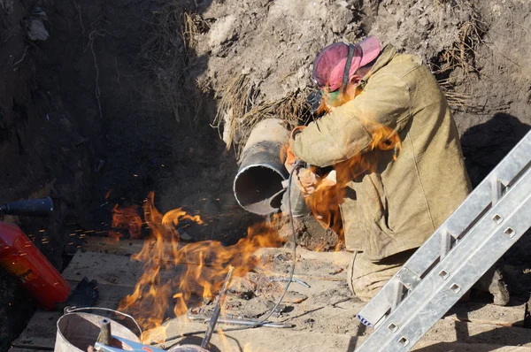 Gáz veszélyes munka. Lakatos a gödör, készítsünk egy csővezeték hegesztés. — Stock Fotó